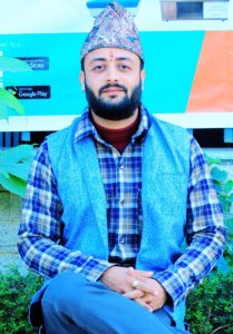 Principal of Narmadeshwar Aadarsha Sanskrit Bidyapheet Gurukul wearing a traditional Nepali Dhaka topi and blue waistcoat.